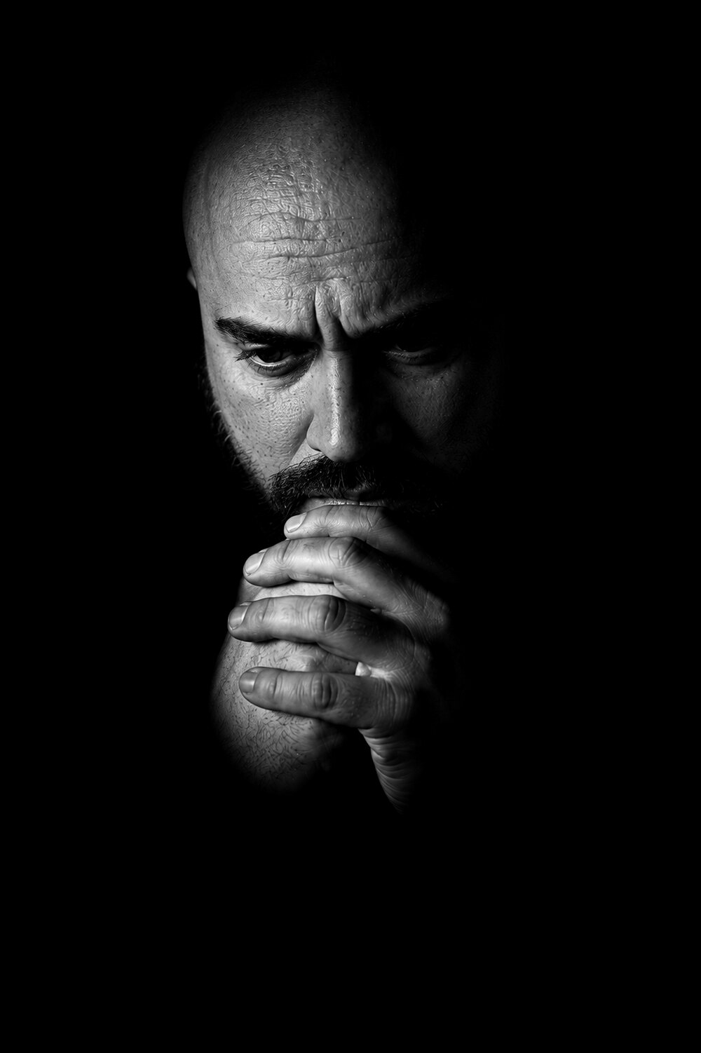 Self-portrait of the artist — his face and hands emerging from darkness