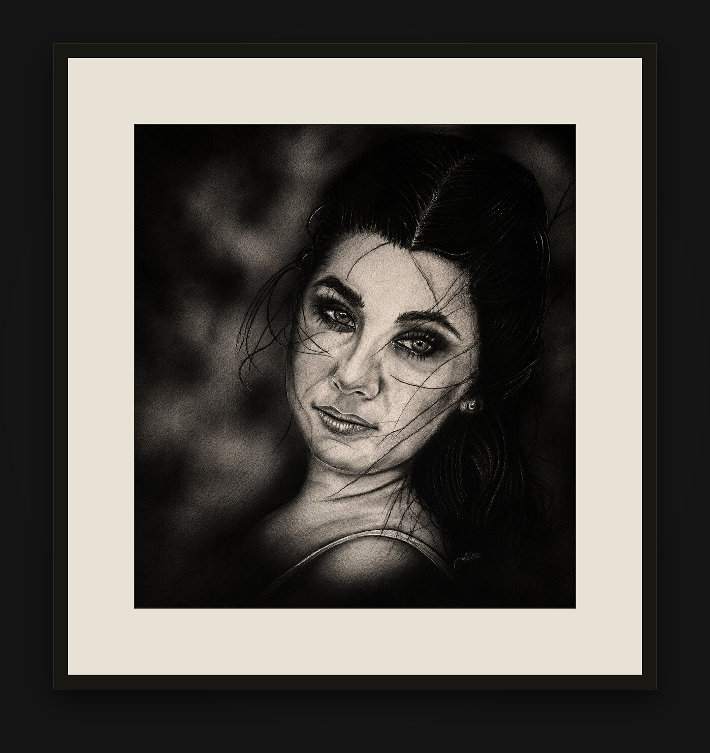 Charcoal and airbrush portrait of a young woman — her face and shoulder emerging from a soft dark background, loose wisps of hair across her face — shown framed on a gallery wall